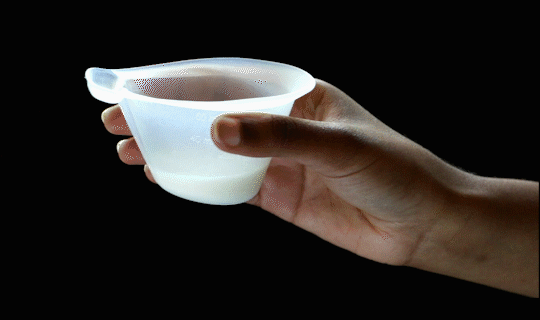 Animated GIF of hand tilting NIFTY cup so milk flows into small reservoir.