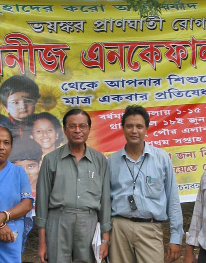 Health center staff with Dr. Mukergee and children standing in front of Japanese Encephalitis poster, West Bengal, India, July 2006
