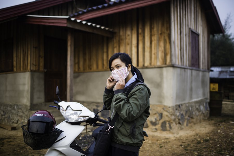 In Laos, Orladee Nonnavongsa alights a motorbike and dons her mask to deliver Japanese Encephalitis vaccines. Vaccines need a strong support system to reach the communities that need them most. Photo: PATH/Aaron Joel Santos.