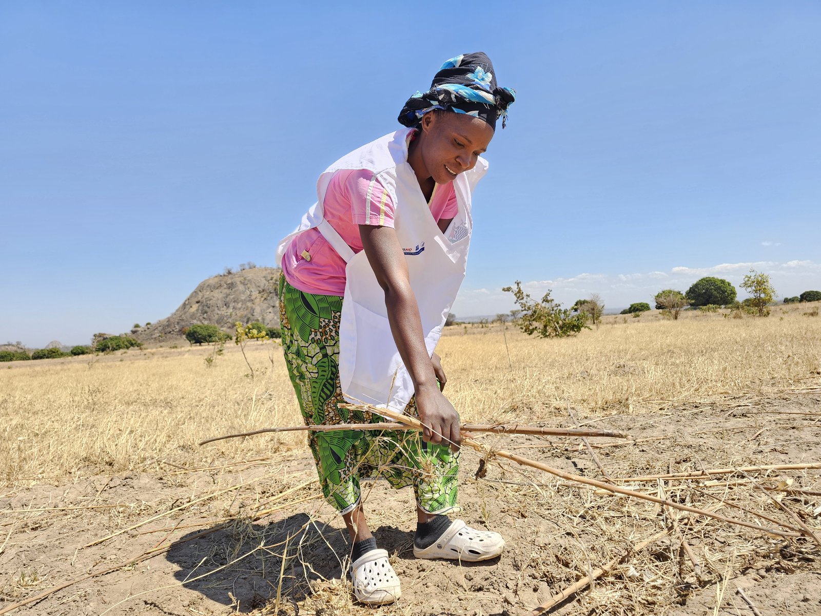 Anne Mwale, a community health worker, inspects withered crop remnants on her drought-affected farm in Chipala village, Petauke District. Photo: PATH.
