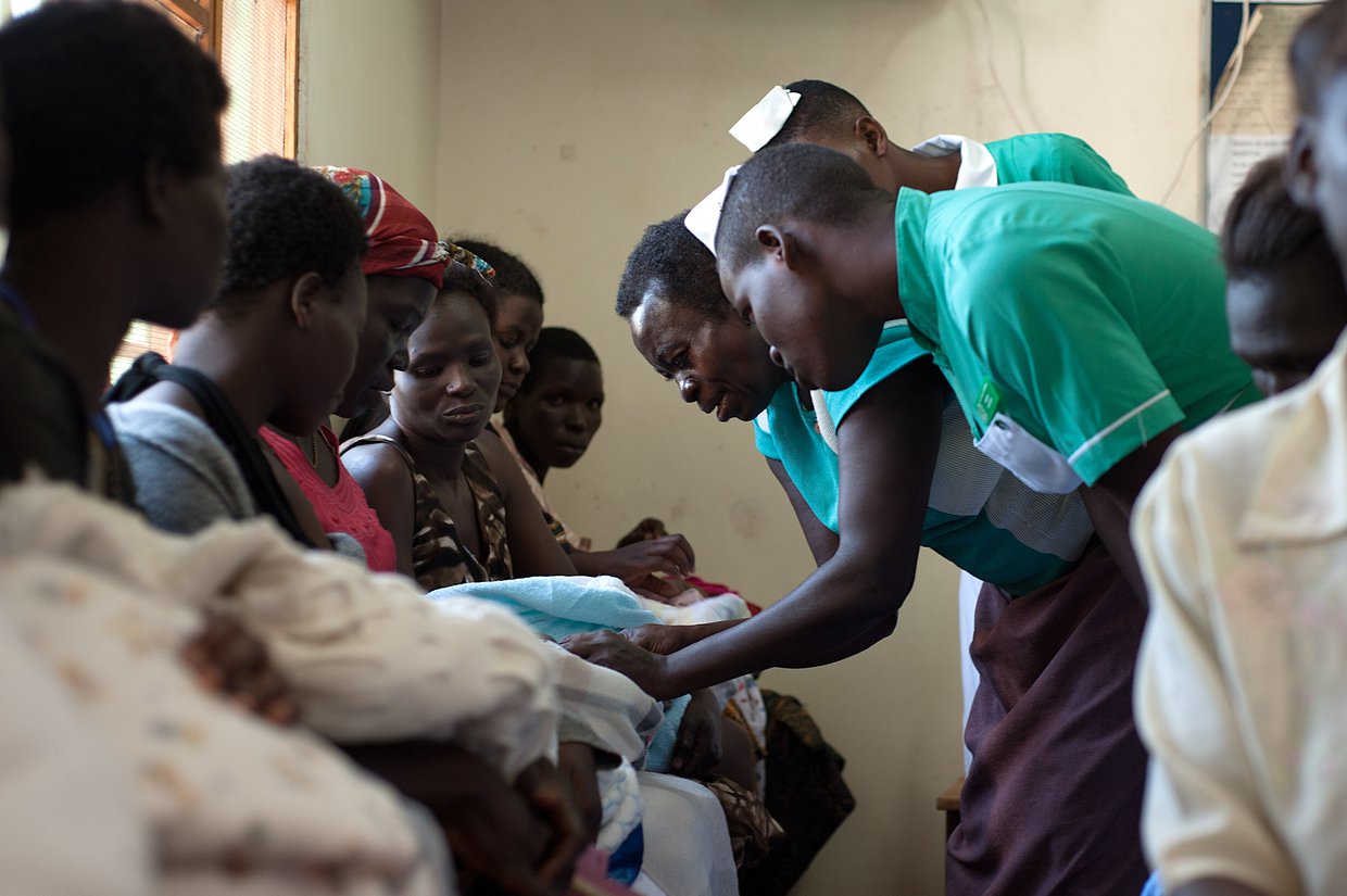Nurses talk to mothers holding their infant children.