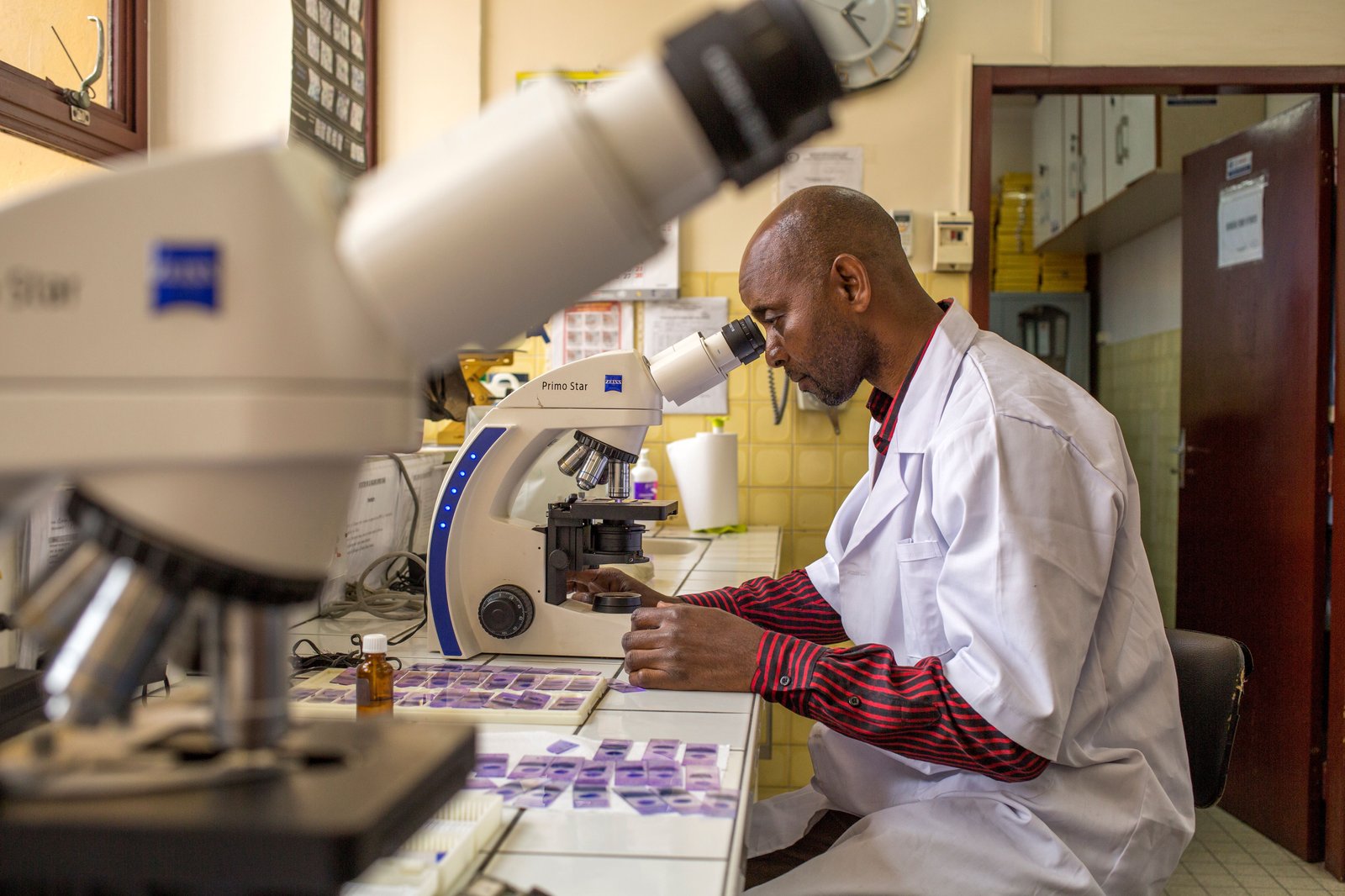 Arthur Dani Hzizidi examines slides for malaria parasites at the Institut National de Recherche Biologique (INRB) in DRC. With PATH/MalariaCARE support, the INRB is helping to build a national archive of malaria slides. Photo: PATH/Georgina Goodwin.