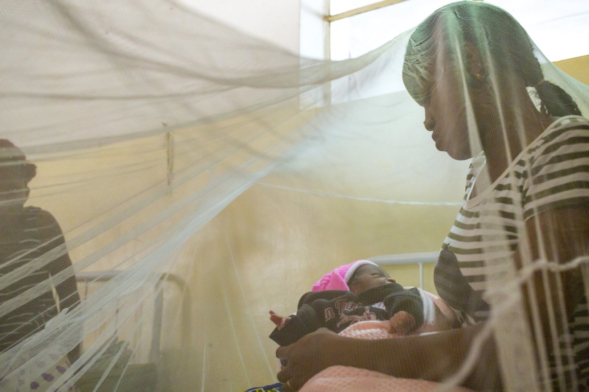 A woman with her newborn baby sitting under a bed net in the maternity room at Sendwe Hospital in the DRC.