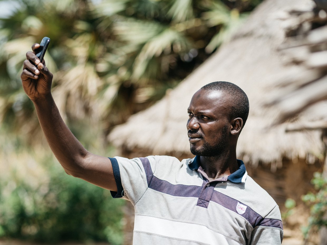 A malaria case investigator holding a cellular telephone to submit data he has collected.