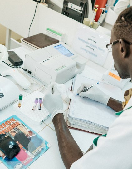 A laboratory worker filling out paperwork in the regional hospital laboratory in Thiès, Senegal. Connected diagnostics have the potential to save health workers valuable time—and accelerate pandemic response times. Photo: PATH/Gabe Bienczycki.