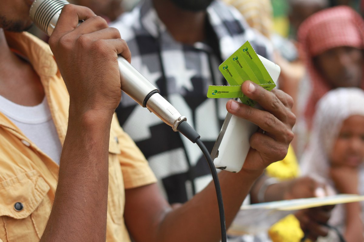 A man, Kedir Birru Mulat, Disease Prevention & Health Promotions Coordinator for Yalo District, conducting immunization advocacy activities at Yalo market. This picture is portraying him doing the phone card competition – one trick to get people to stay a