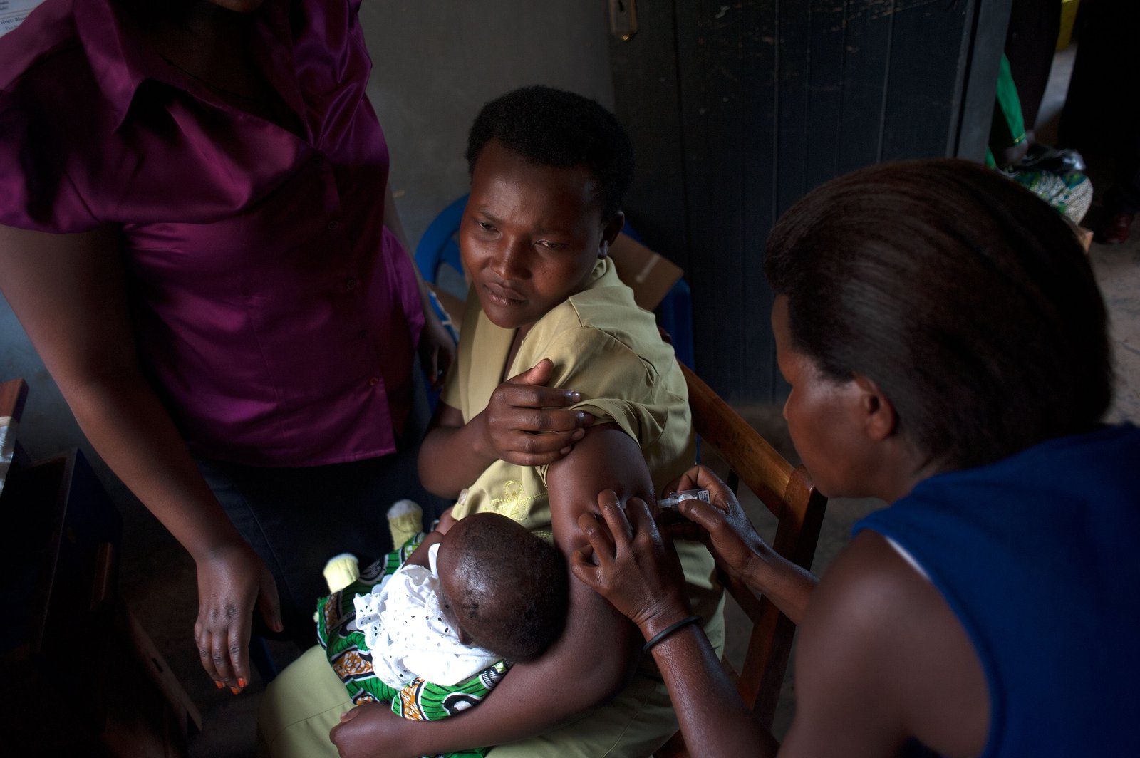 A woman holds her baby while receiving an injection.