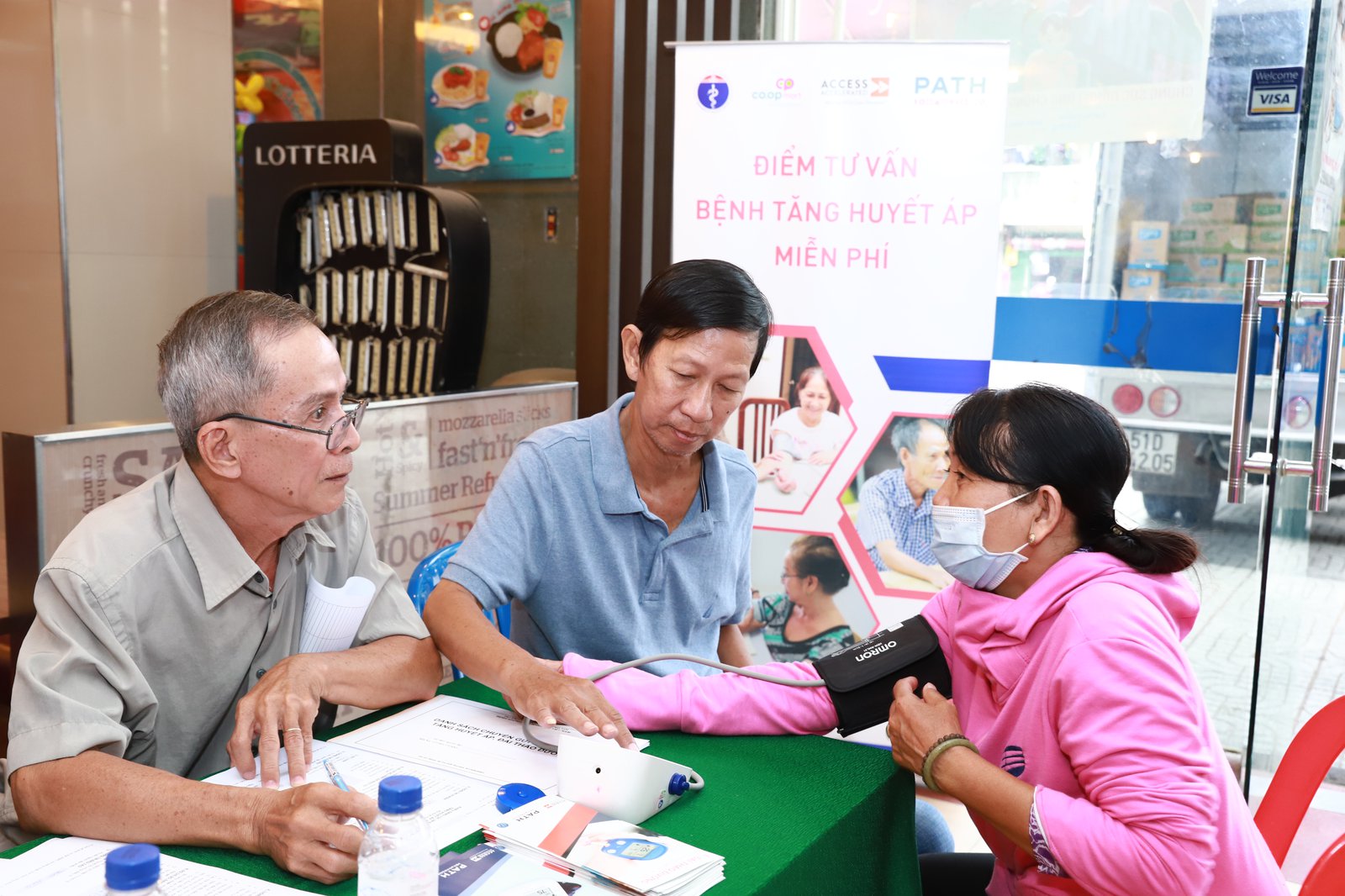 Community volunteers screen a Co.opMart customer for hypertension.  Photo: PATH/Hung Nguyen Manh.