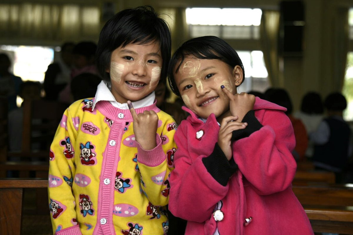 Two young girls holding up fingers stained with dye.