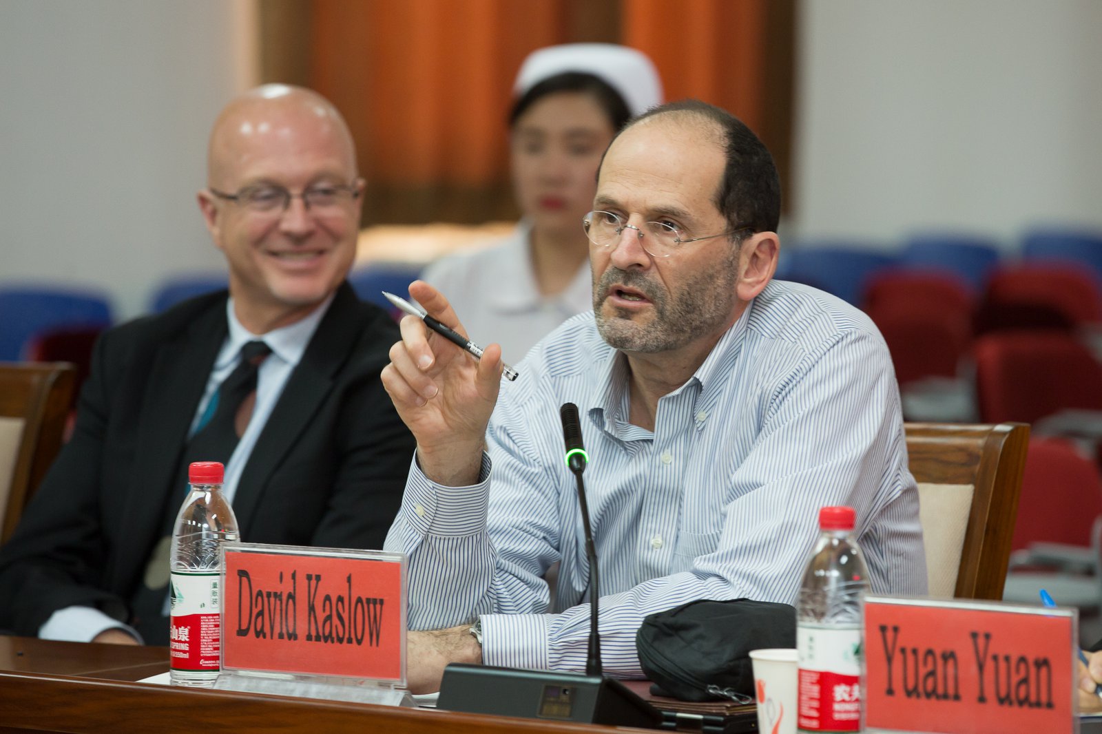David Kaslow speaks and gestures while Steve Davis, who is sitting next to him, looks on smiling.