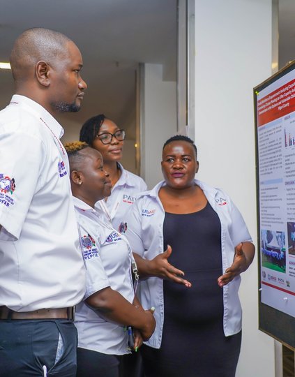 Trizah Ouma, PATH Program Officer, discusses her poster on supporting community health volunteers who serve as caseworkers for orphans and  children vulnerable to HIV in Migori County. Photo: PATH.