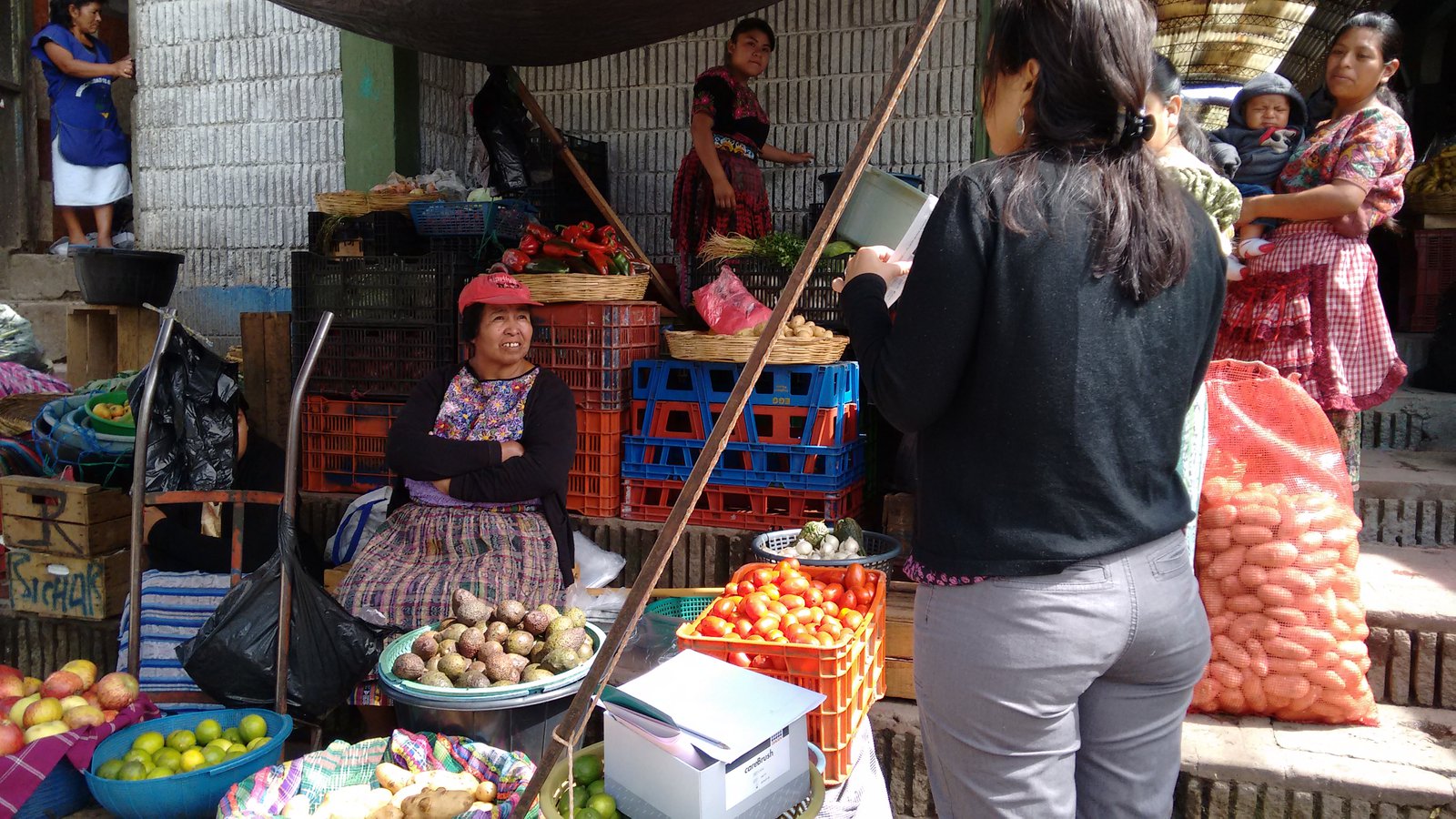 Women talking in an open-air produce market. 