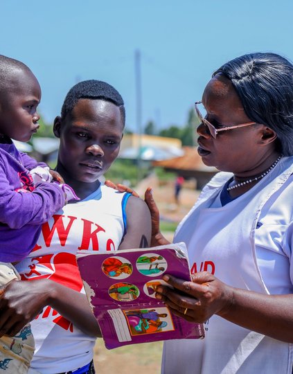 Kendu Bay Sub-County Hospital Vaccines and Immunization Coordinator, Victorine Wasonga (right), speaks with Jane Awuor and her 2-year-old child, Shirley Marion, about the importance of timely childhood vaccination against life-threatening diseases.