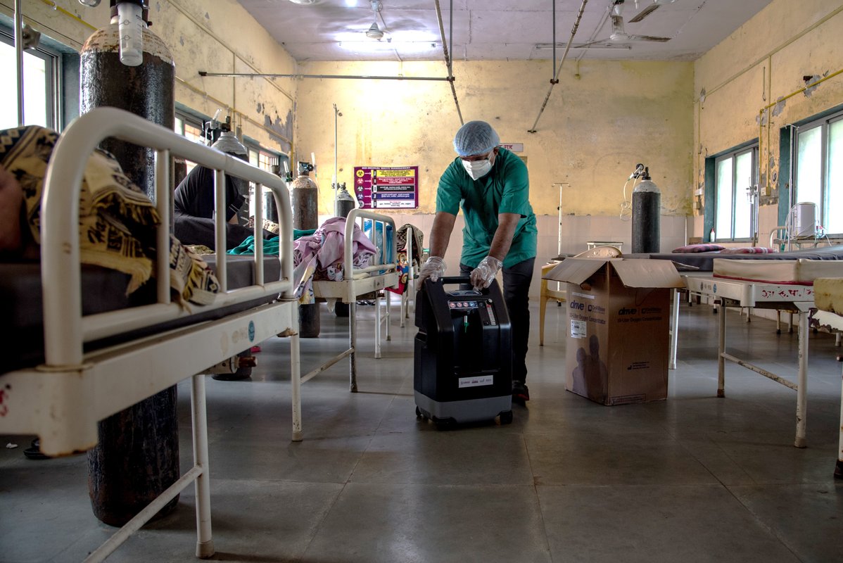A health care worker unpacks and installs an oxygen concentrator for a COVID-19-positive patient inside an isolation ward at Rural Hospital in Palghar, Maharashtra, India. Photo: PATH/Ragul Krishnan.