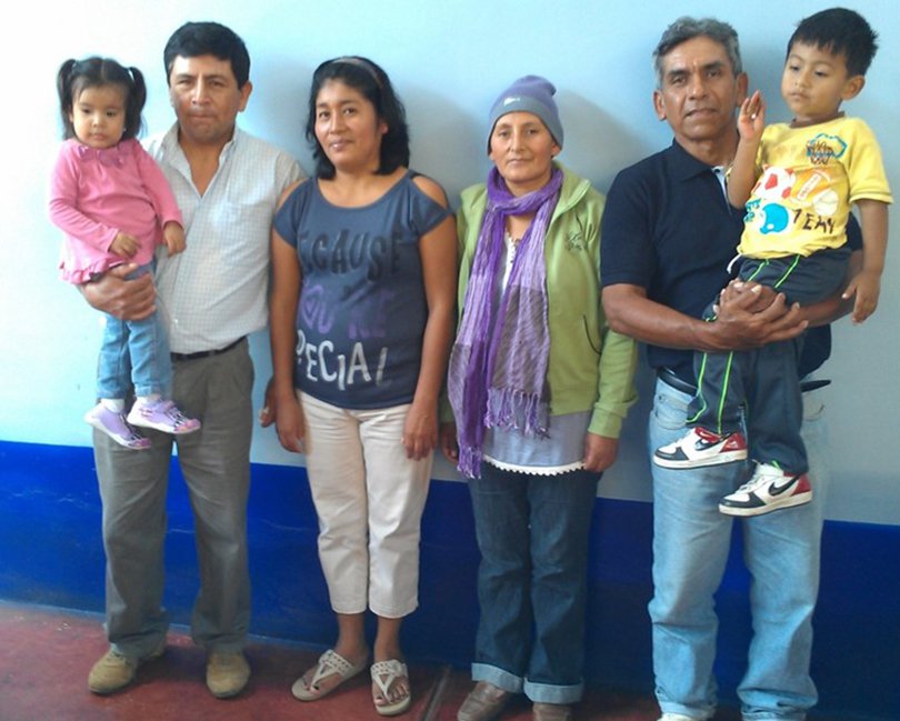 Two familes stand with their children in their arms. 