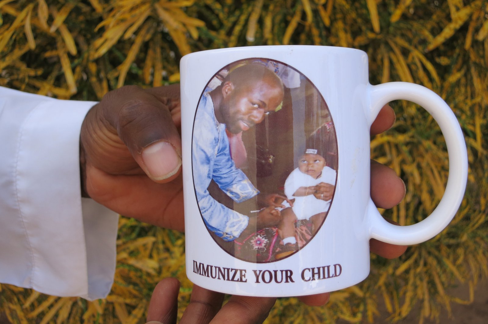 Mug with photo of a man vaccinating an infant, with text, "Immunize your child."