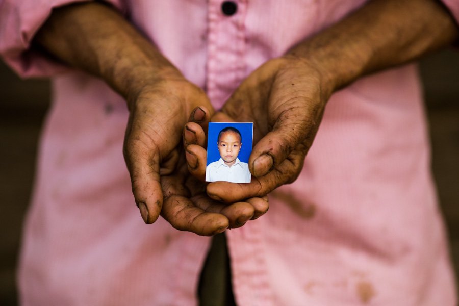 A pair of hands holding a small photograph of a boy.